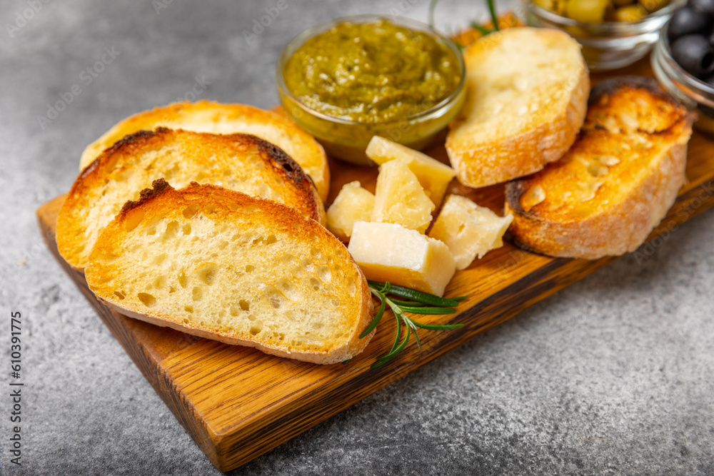 Italian ciabatta bread cut in slices with herbs, olives, pesto sauce, garlic and parmesan cheese on a concrete table. Fresh homemade Italian Ciabatta bread sliced with herbs and spices.Place for text. Italian ciabatta bread cut in slices with herbs, olives, pesto sauce, garlic and parmesan cheese on a concrete table. Fresh homemade Italian Ciabatta bread sliced with herbs and spices.Place for text.