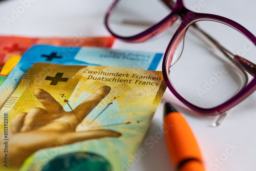 Swiss francs money, women's glasses, white sheet of paper, pen, concept, bill payments, installments and credits, rising household budget costs in Switzerland photo