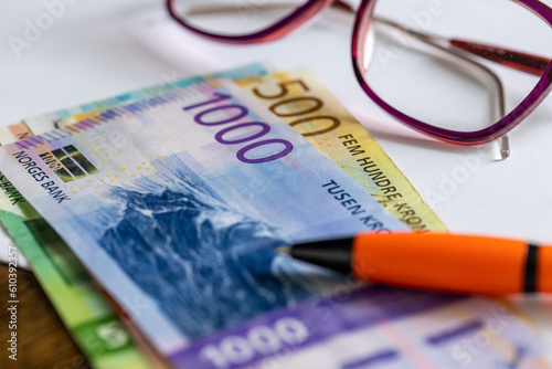 Fotografie Norwegian krone money on the desk next to Women's Glasses, a white sheet of pape