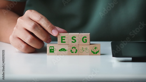 Concept of Environmental, Social and Governance, ESG sustainability. Woman hand arranging wood cube with clean energy icons.