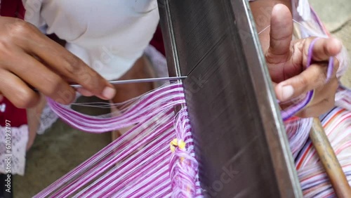 A woman's hands attach the yarn parallel to the steel thread for cloth weaving.  photo