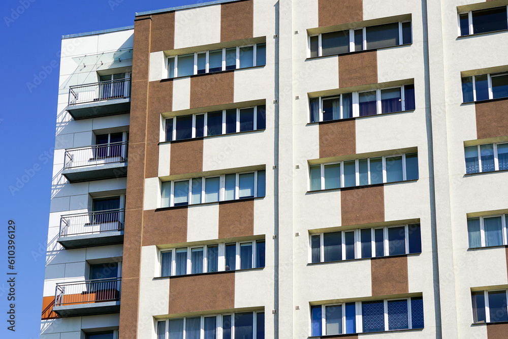 Renovated and insulated multistorey apartment building facade fragment against a blue sky background