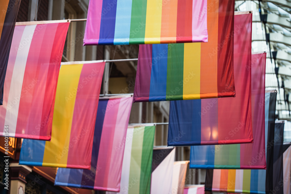 Naklejka premium Different LGBTQ pride and rainbow flags hanginging in two rows in city arcade. London