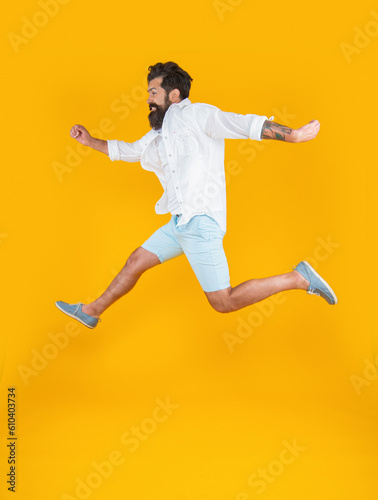 image of happy bearded guy in a hurry wearing summer fashion isolated on yellow background