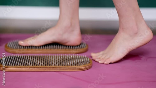 close up standing barefoot woman doing nail reflexotherapy at professional yoga class feet of female person on sadhu boards on pink mat in spacious studio effective body relaxation practice closeup photo