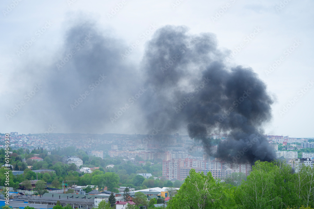 Black smoke rises over buildings and trees. Emergency concept.