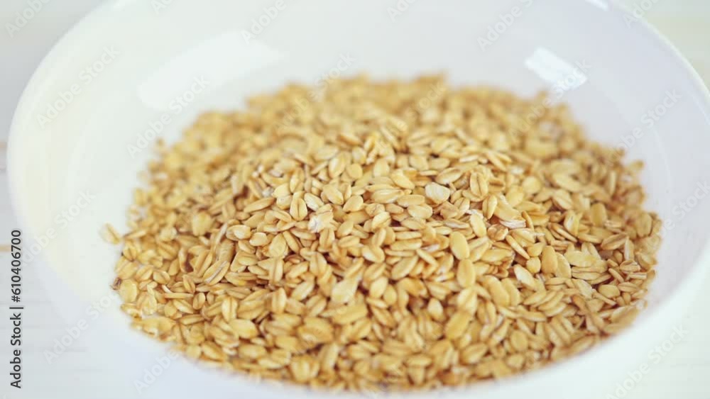 Oatmeal or rolled oats falling into white bowl. Healthy breakfast. Slow motion Oatmeal or rolled oats falling into white bowl. Healthy breakfast. Slow motion