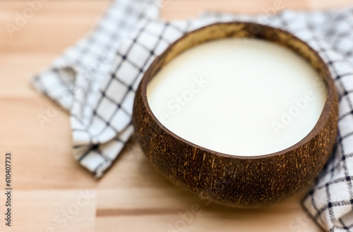 Shell with coconut milk and napkin on wooden background