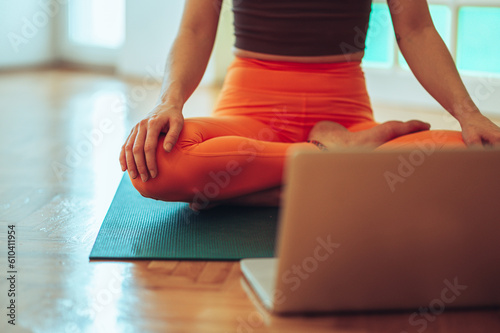 Girl's legs in a vivid orange leggings while sitting in front of the laptop.