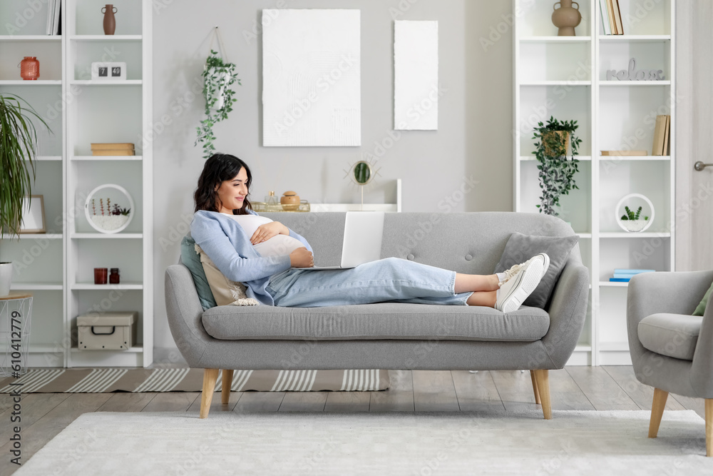 Young pregnant woman working with laptop on sofa at home Young pregnant woman working with laptop on sofa at home