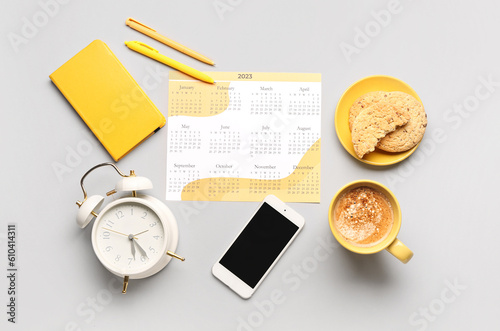Composition with calendar, mobile phone, alarm clock, cup of coffee and cookies on grey background