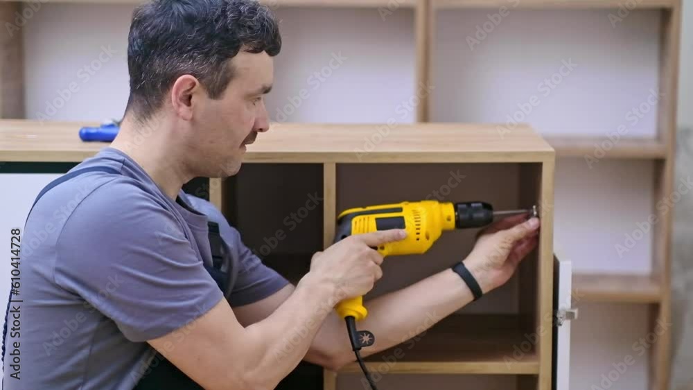 Custom furniture production focused handyman attaching door fastener to wooden cabinet for office high-quality woodwork materials for skilled specialist in coveralls Custom furniture production focused handyman attaching door fastener to wooden cabinet for office high-quality woodwork materials for skilled specialist in coveralls