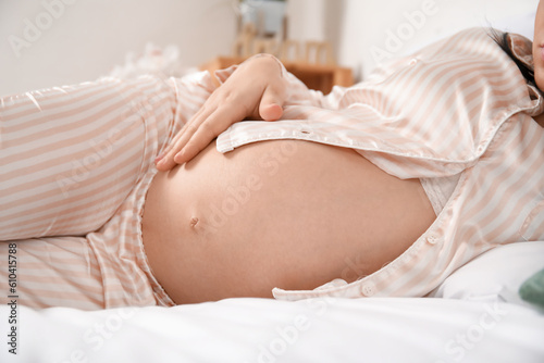 Young pregnant woman lying in bedroom, closeup