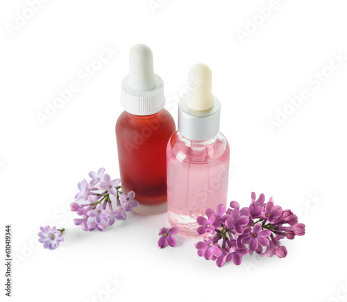 Bottles of cosmetic oil with beautiful lilac flowers on white background