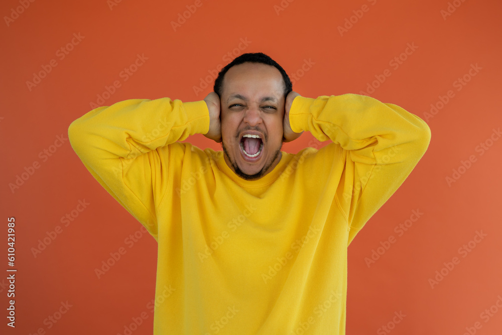 Portrait of positive young black man looking at camera screaming and closing ears with hands Portrait of positive young black man looking at camera screaming and closing ears with hands