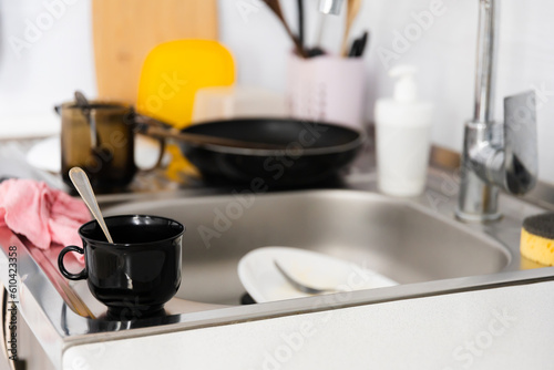 Side view on white kitchen with unwashed dirty dishes on the countertop utensils and kitchen appliances in a mess after cooking