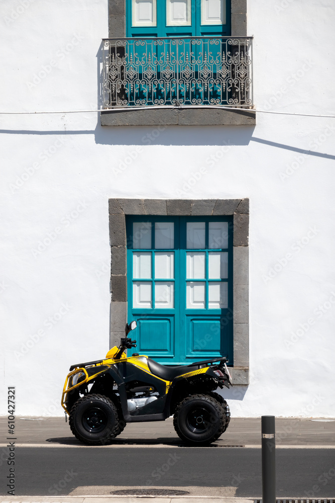 Fototapeta premium A quad parked on the street in front of a blue vintage window. Off-road motorcycle.