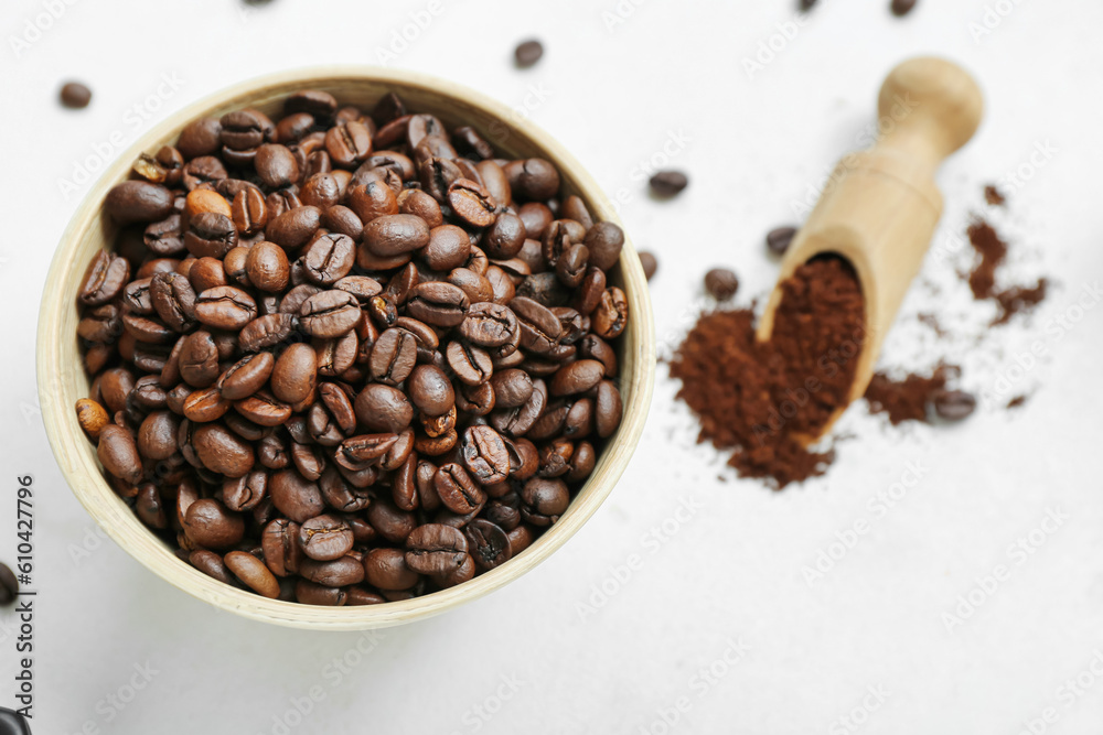 Naklejka premium Fresh roasted coffee beans in wooden bowl with ground coffee powder and scoop on white background, freshly roasted coffee beans fill a rustic wooden bowl, ready for grinding and brewing