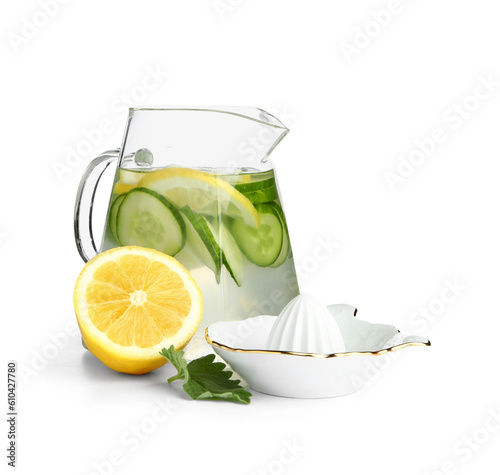 Jug of infused water with cucumber slices and juicer on white background