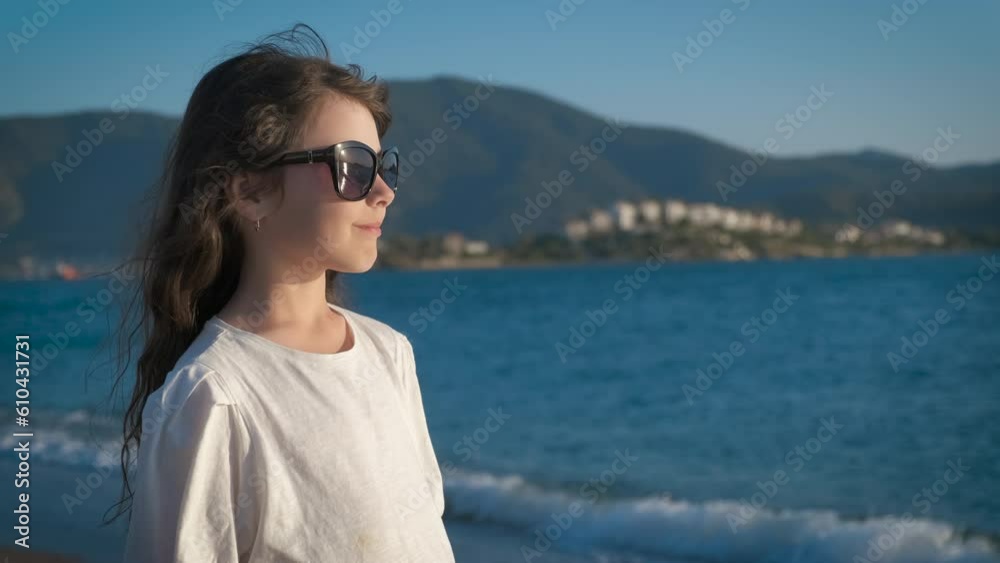 Child at sunset against the backdrop of the blue sea. A little girl enjoys the sea breeze at sunset. Child at sunset against the backdrop of the blue sea. A little girl enjoys the sea breeze at sunset.