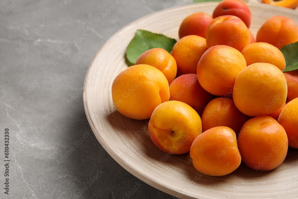 Plate with fresh apricots on grey background Plate with fresh apricots on grey background