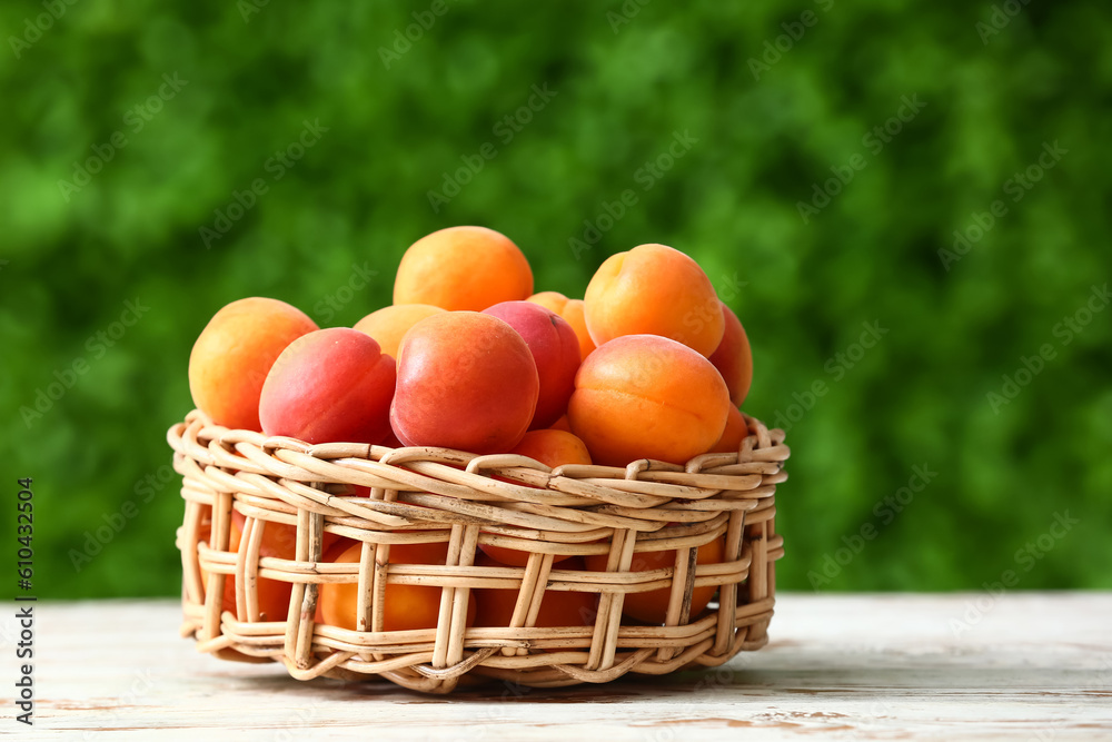Wicker bowl with fresh apricots on white wooden table outdoors