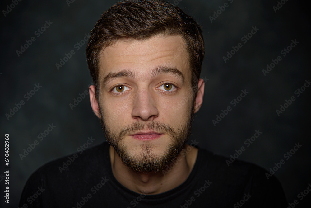 Portrait of an attractive young man with a beard on a dark background.