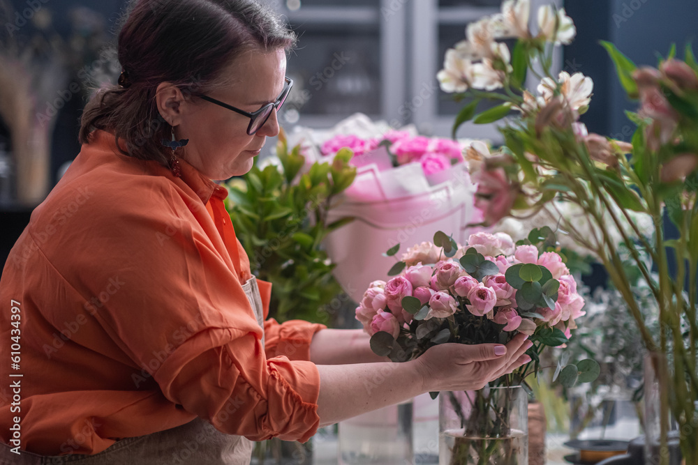 flower shop assistants florist with laptop working, checking orders, lot of flowers around interior. small business concept.