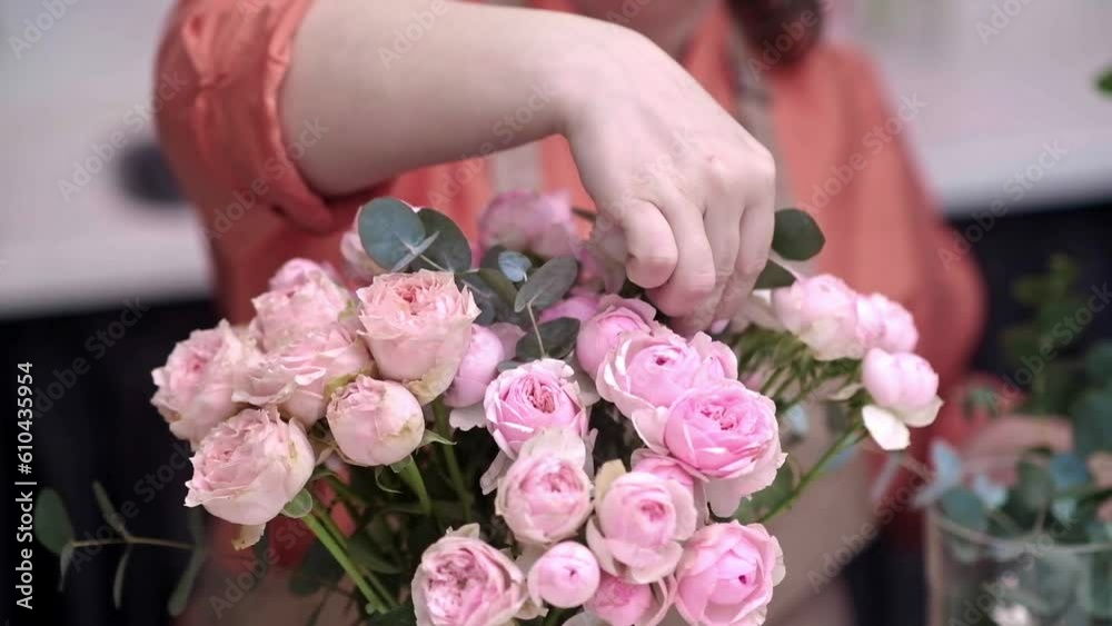 love for flowers, the successful female business owner of the flower shop mixing proudly with a gorgeous bouquet of pink roses, a testament to her hard work and dedication.