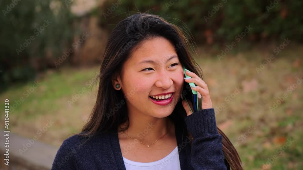 Joyful teenage female student smiling and having a cellphone call conversation. Happy carefree young chinese woman talking by smartphone outside. Asian gossip lady using a mobile phone to communicate Joyful teenage female student smiling and having a cellphone call conversation. Happy carefree young chinese woman talking by smartphone outside. Asian gossip lady using a mobile phone to communicate