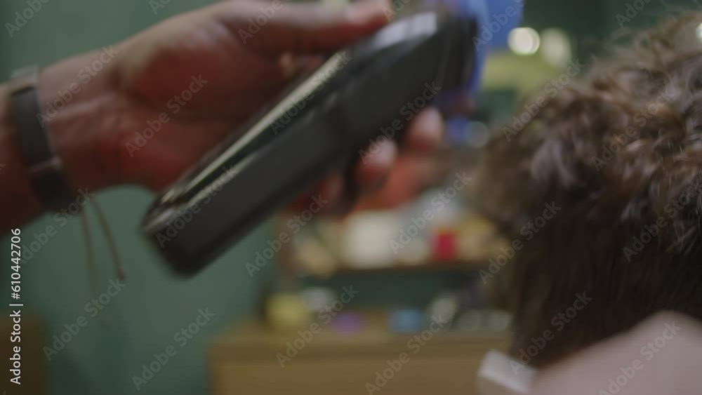 Close-up shot of hands of unrecognizable barber using hair clippers and comb for trimming hair on back of client neck Close-up shot of hands of unrecognizable barber using hair clippers and comb for trimming hair on back of client neck