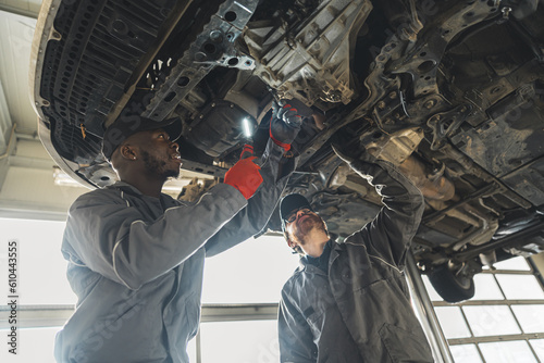 Two male auto mechanics replacing a clutch in a car on hydraulic lift, low angle shot. High quality photo