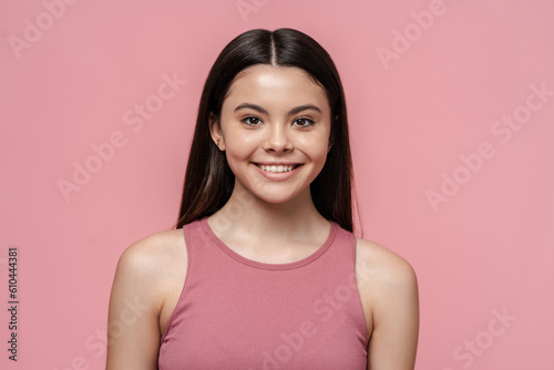 Portrait of cute, beautiful teenage girl in pink top looking at camera, isolated on pink background © speed300