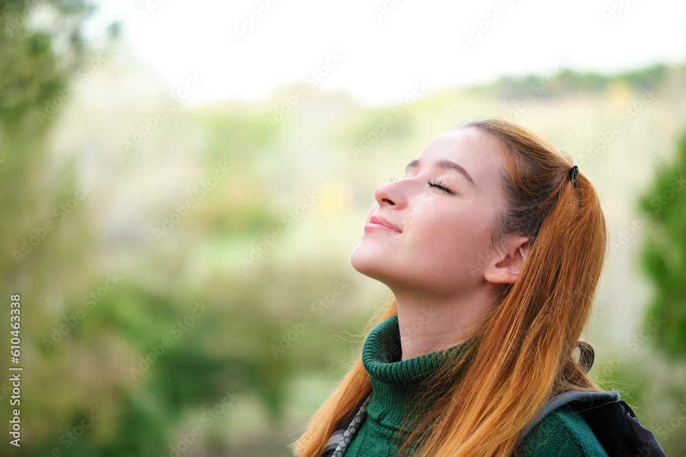 Smiley redhead young woman breathing fresh air standing outdoors. Smiley redhead young woman breathing fresh air standing outdoors.
