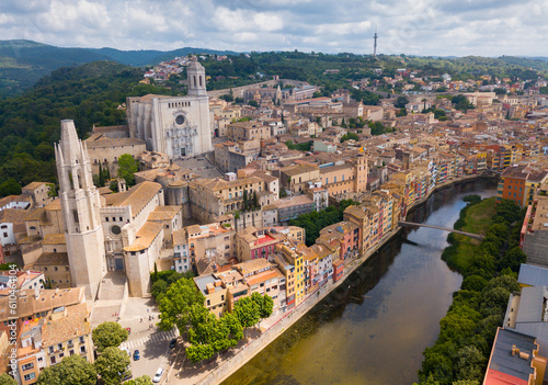 View from drone of residential areas of Spanish town of Girona on bank of Onyar river with Cathedral and Collegiate Church