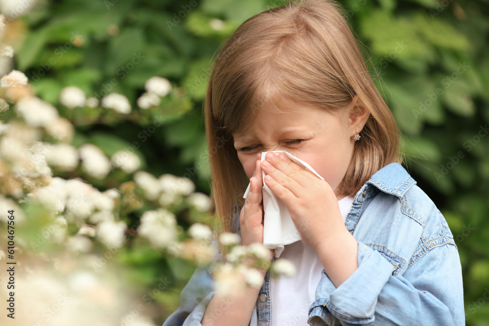 Little girl suffering from seasonal pollen allergy near blossoming tree on spring day Little girl suffering from seasonal pollen allergy near blossoming tree on spring day