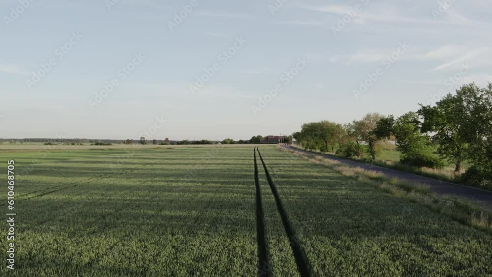 rising above a green farmland on a sunny day, next to a road and a passing red car rising above a green farmland on a sunny day, next to a road and a passing red car
