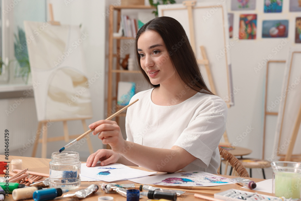 Fototapeta premium Beautiful young woman painting in studio. Creative hobby