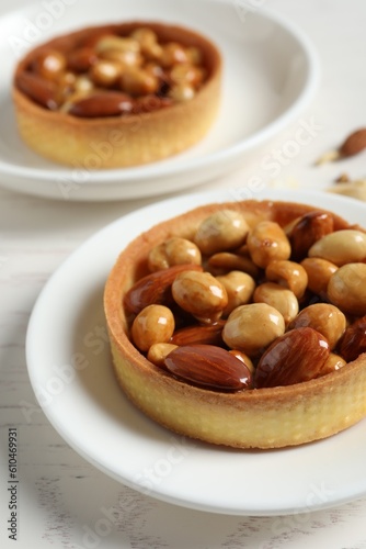 Tartlets with caramelized nuts on white wooden table, closeup. Tasty dessert