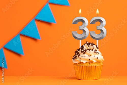 Birthday cake with candle number 33 - Orange background
