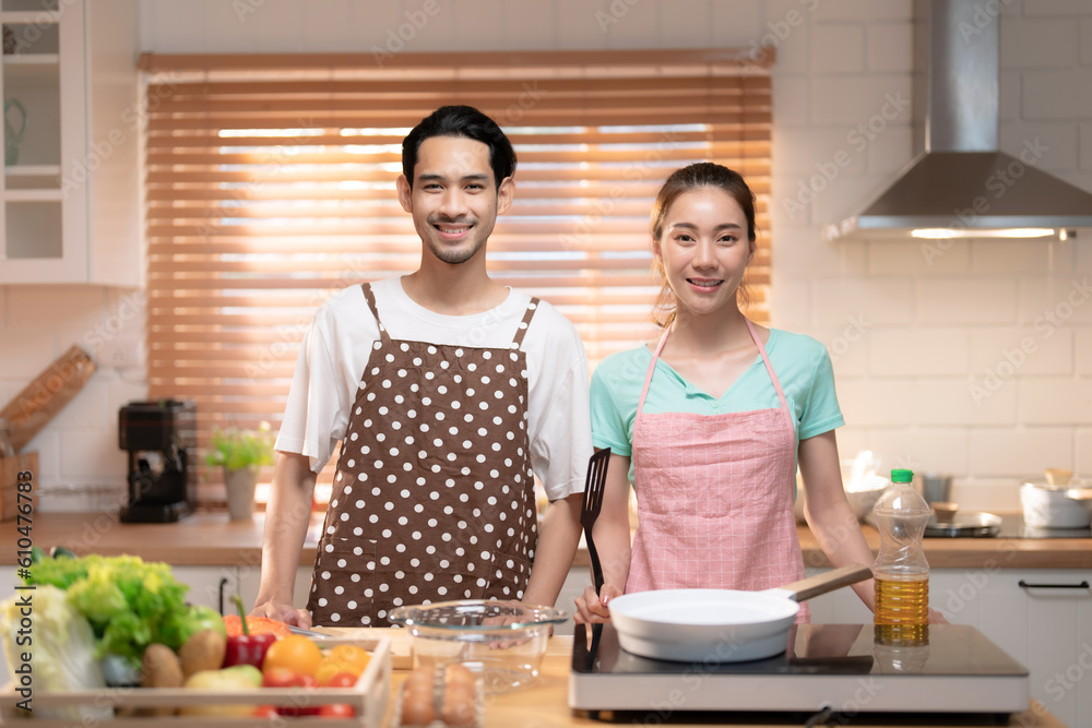 Happy Asian couple preparing delicious dinner in the kitchen at home.