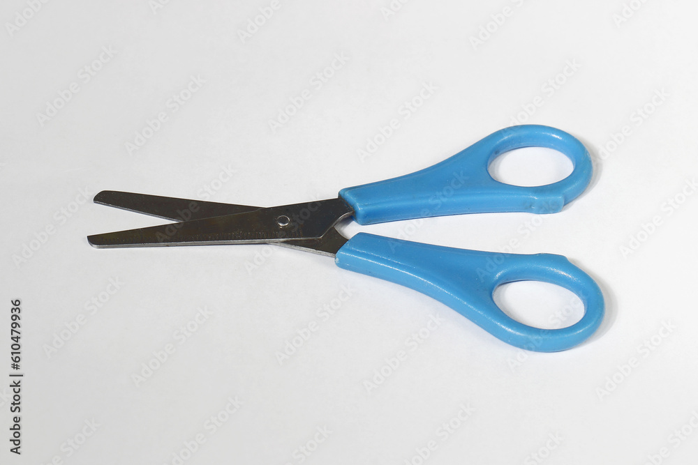 Metal and blue plastic scissors layed on white surface Metal and blue plastic scissors layed on white surface