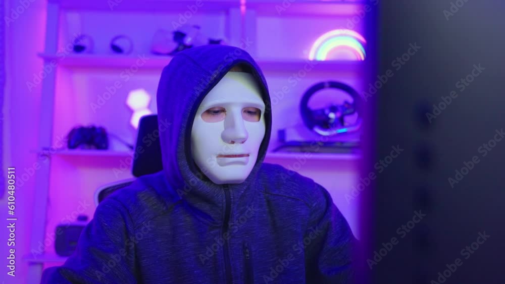 Short of computer hacker wearing white mask stealing data from a laptop. Short of computer hacker wearing white mask stealing data from a laptop.