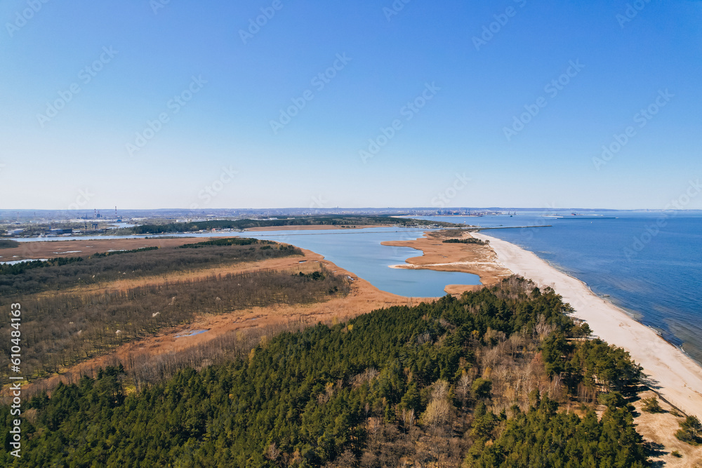 Aerial view drone of river goes into the sea. Delta of Vistula river goes in Baltic Sea in Sobieszewo Gdansk Poland. Forest and small village around river
