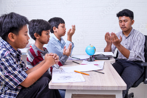 Photography Teacher and students at classroom doing morning prayer with closed eyes