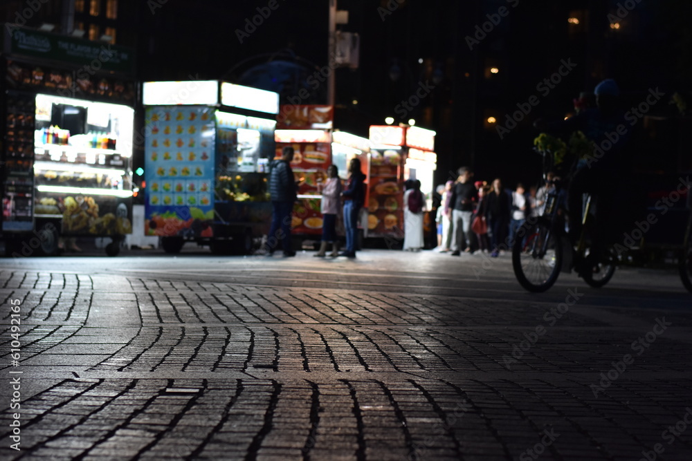 Brick Sidewalk at Night in New York City, Blurred Vendors on Street