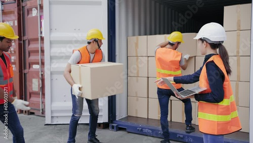 Foreman and a worker help opening containers together and lifting the box  while female assistant check stock by computer at the transport warehouse. Cargo container and Transport Logistic concept