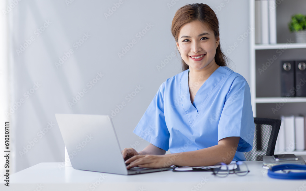 Happy doctor Portrait of young asian woman nurse or doctor smiling using a laptop writing content at consultation Happy doctor Portrait of young asian woman nurse or doctor smiling using a laptop writing content at consultation