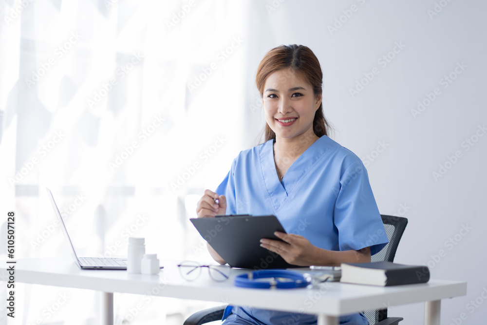 Happy doctor Portrait of young asian woman nurse or doctor smiling using a laptop writing content at consultation Happy doctor Portrait of young asian woman nurse or doctor smiling using a laptop writing content at consultation