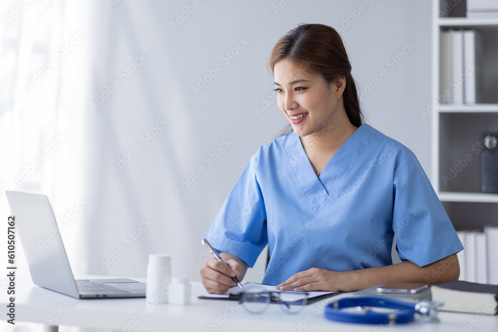 Happy doctor Portrait of young asian woman nurse or doctor smiling using a laptop writing content at consultation Happy doctor Portrait of young asian woman nurse or doctor smiling using a laptop writing content at consultation